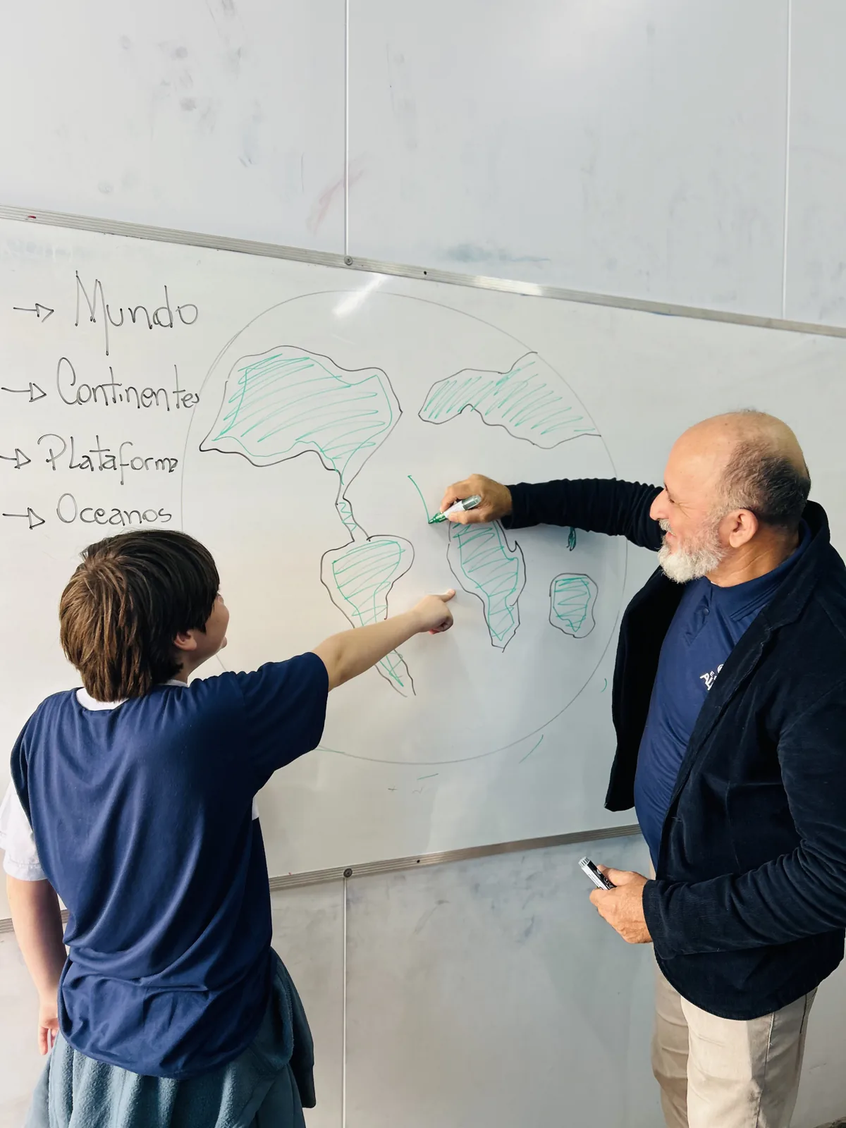 Professor acompanha aluno em atividade no quadro no Colégio Alpha X