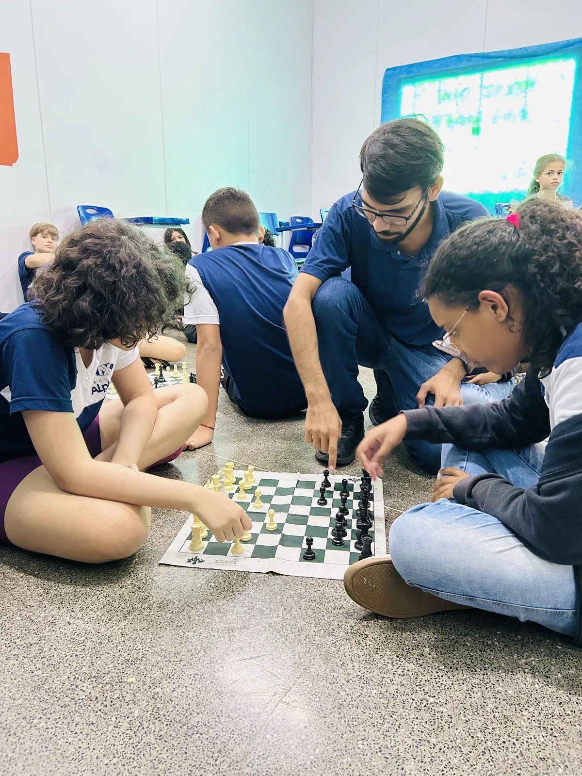 Alunos e professor em atividade de xadrez no Colégio Alpha X