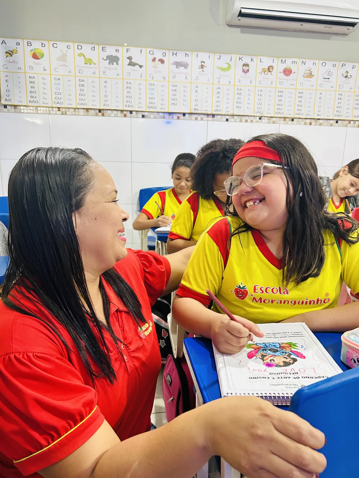 Professora e aluna com material de atividade em sala