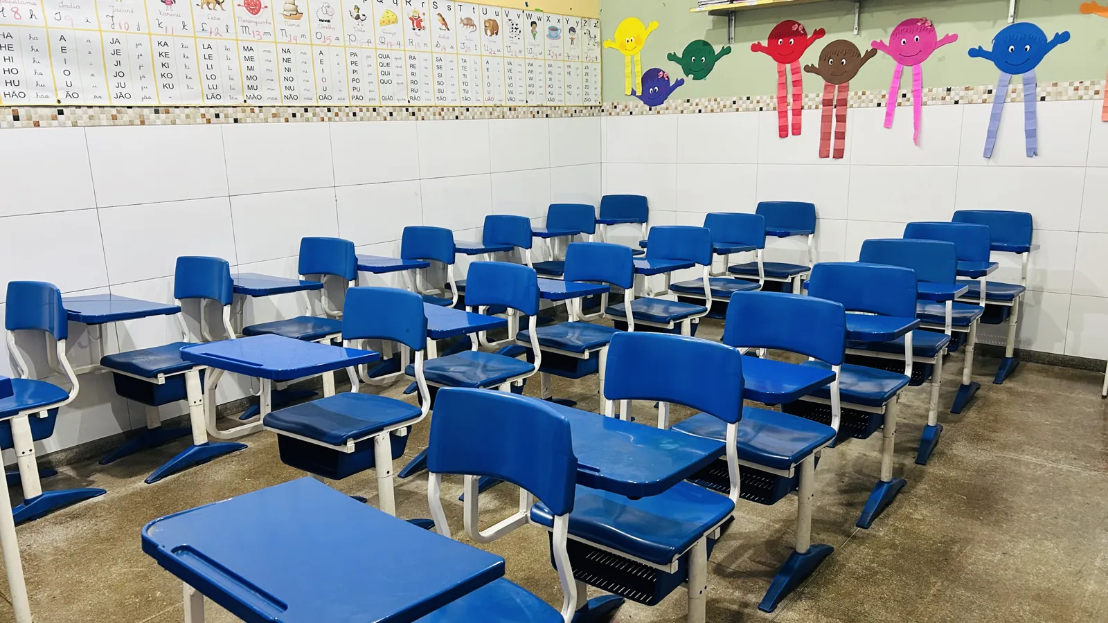 Sala de aula com carteiras azuis e quadro na escola